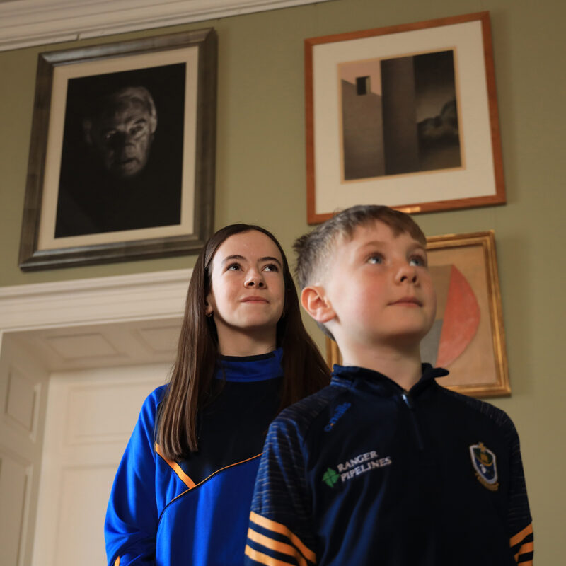 Young visitors posing in front of a photo of their grandfather o